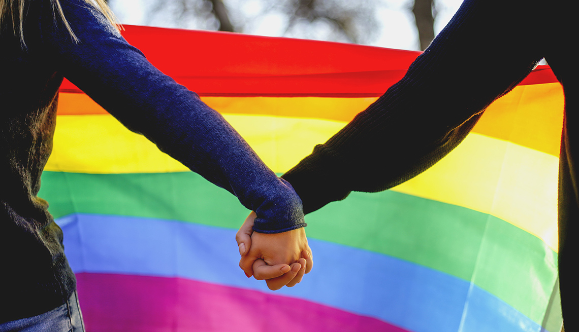 Two lesbian girls holding hands and rainbow flag